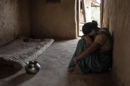 A woman sitting in a bare room