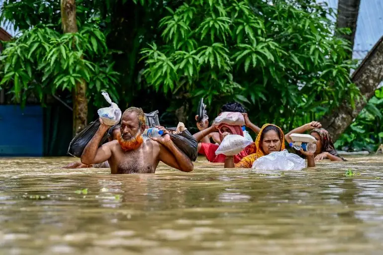 Families walking rice and bags through the water