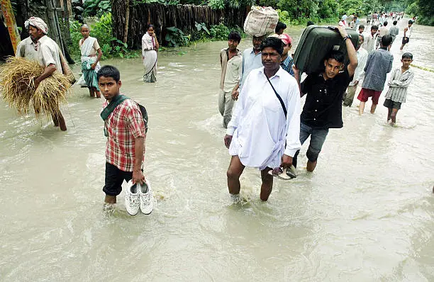 A whole village walking through a river, carrying what they could save