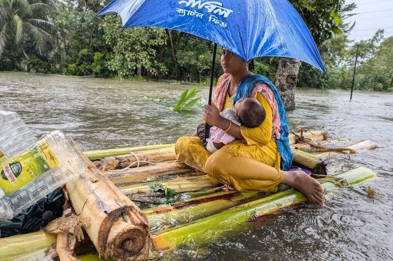A woman and infant on a raft of bamboo
